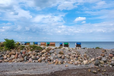 Beach chairs stand along a rocky coast under a partly cloudy sky, Hohwacht, Schleswig-Holstein,