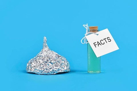 Concept for fighting conspiracy theories with facts with tinfoil hat and cure bottle with word