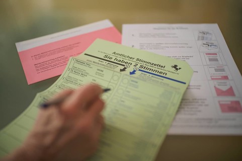 Voting, woman holding ballpoint pen, fills out ballot papers, votes, absentee ballot, official
