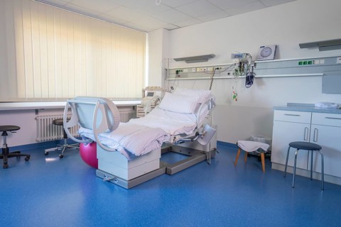 A birthing room with blue floors and a modern hospital bed, delivery room of the new gyn and