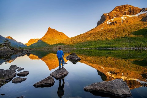 Young man standing on a rock in water, enjoying the landscape, picturesque mountain landscape with