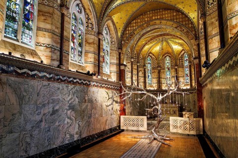 Silver tree sculpture stands beneath stained glass in the marble chancel of Fitzrovia Chapel,