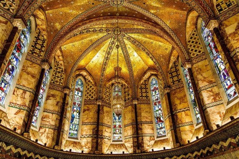 Gilded mosaic vaulting and stained glass windows illuminate the apse of the Grade II listed