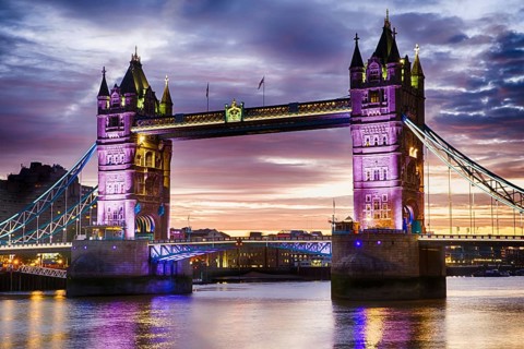 Tower Bridge's Neo-Gothic towers glowing purple over the Thames at dusk, London, United Kingdom