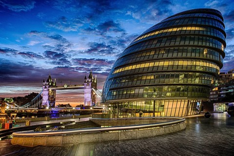 City Hall's curved glass facade beside Tower Bridge at dusk, London, United Kingdom