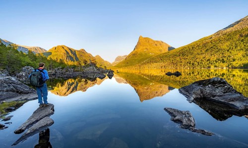 Young man standing on a rock, enjoying the landscape, picturesque mountain scenery in the
