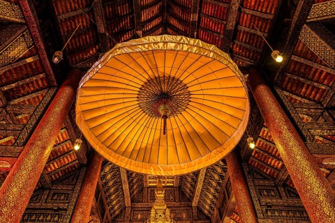 Artfully decorated interior with traditional parasol under richly decorated wooden roof