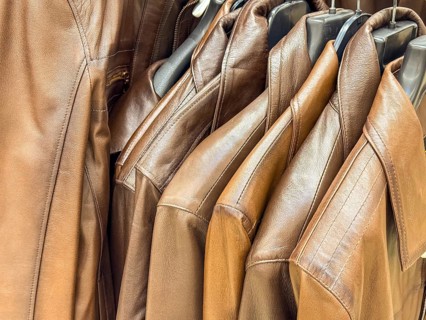 A collection of brown leather jackets hanging on a rack. The jackets are neatly arranged,
