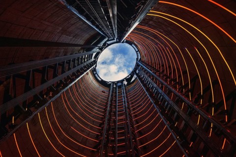 Illuminated rings spiral upward inside one of Battersea Power Station's rebuilt chimneys, framing a