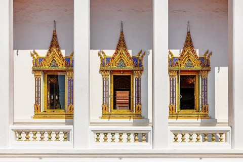 Traditionally decorated temple windows with golden ornaments in symmetrical architecture of a
