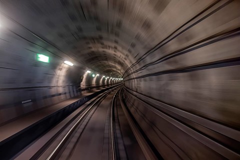 Ein beleuchteter Tunnel mit Gleisen vermittelt ein Gefühl von Geschwindigkeit und Urbanität,