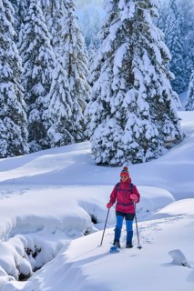 Nice and active senior woman hiking with snow shoes in deep powder snow in the Hochhaedrich area of