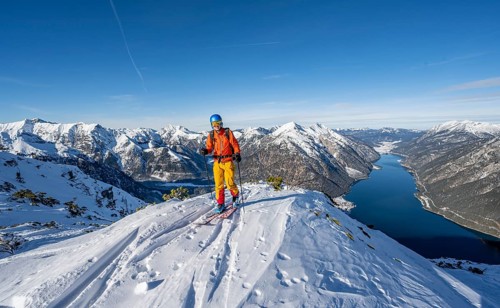 Picturesque view of Achensee and wintry mountain scenery, ski tourers at the summit of Bärenkopf,