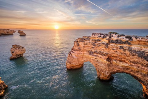 Sunrise view of Praia da Marinha beach in Algarve, Portugal, with a limestone sea arch, Atlantic