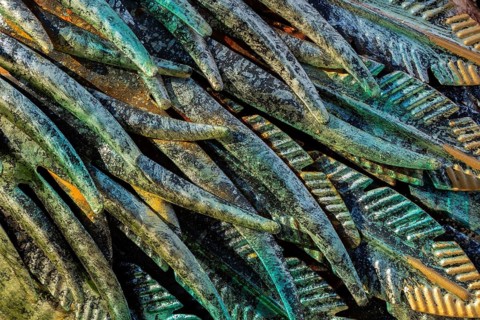 Close-up of golden, greenish and turquoise painted carved metal feather details on ornamental