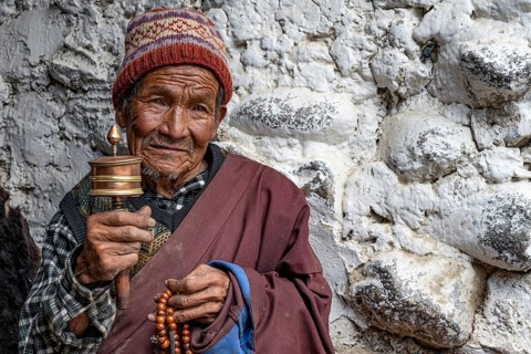 Elderly man with Buddhist stone mill and prayer necklace, Mala, in traditional dress, Lo Manthang,