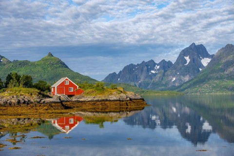 Red fishing hut on the shore, Rorbuer hut, picturesque fjord landscape at Raftsund fjord, mountains
