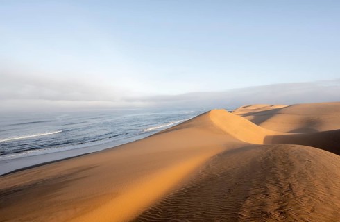 Sand dunes and sea in morning light, Atlantic coast and Namib desert, impressive desert landscape,