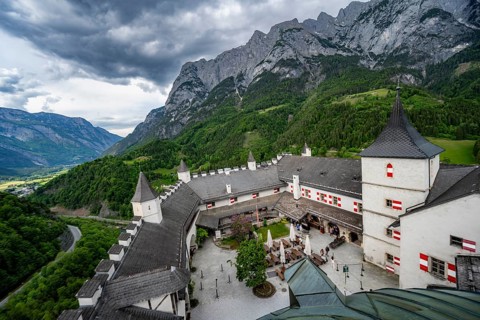 Castle with courtyard, mountain peaks of the Tennengebirge Mountains at the back, dramatic clouds,
