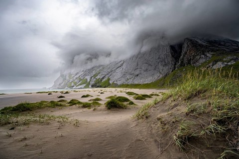 Sand dunes on sandy beaches Bunesstranden between rocky mountain peaks and dramatic clouds,