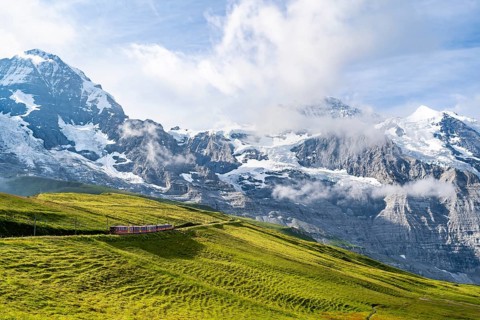 Jungfrau Railway to Jungfraujoch runs through green meadows, above the Kleine Scheidegg stop, rack