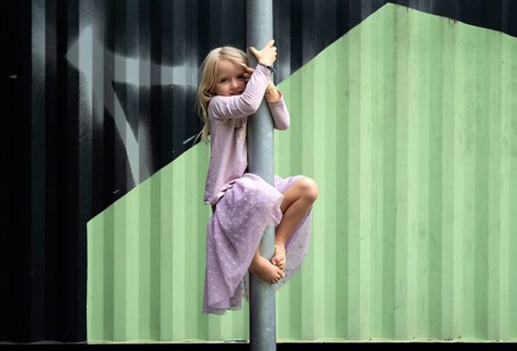 Girl, blonde, 5 years old, dress, gymnastics on climbing pole, climbing frame, smiles, playground,