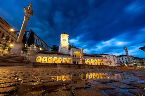 Illuminated main square Piazza della Libertà with Loggia e Tempietto di San Giovanni and clock