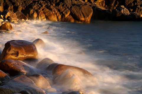 Stones, pebbles, pebbles, washed by water, waves, spray, motion effect, long exposure, evening