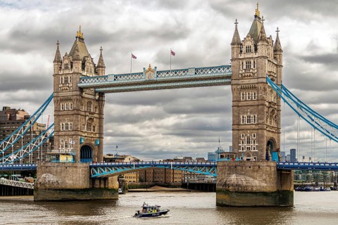 The Victorian bascule towers of Tower Bridge rise above the River Thames as a river police patrol