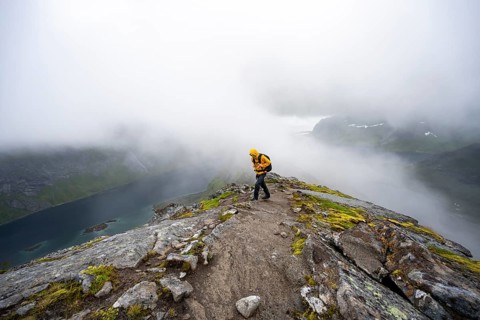 Hikers on Helvetestinden summit, covered in clouds, Lofoten, Norway