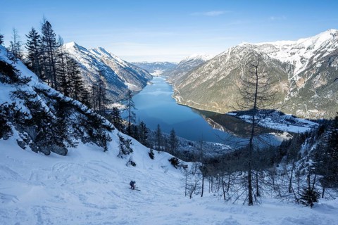 Picturesque view of Achensee and wintry mountain scenery, ski tourers descending from the summit of