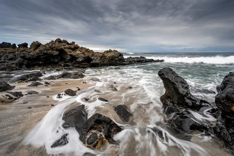 Waves blaze on the beach, rocky coast with volcanic stones, long exposure, Playa de la Pequeña,