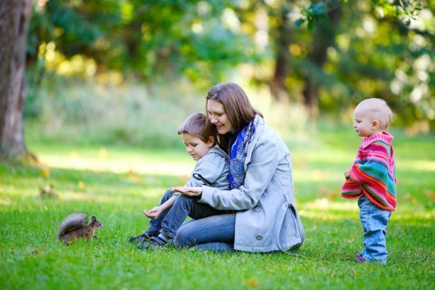 A young mother and two children watch a squirrel in the park, Finland, Scandinavia