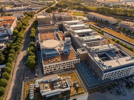 Large-scale complex of modern buildings with distinctive roof structures, construction site of the