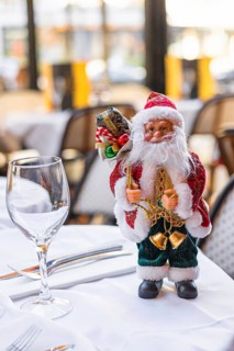 A decorative Santa Claus figurine stands on a table. The Santa has a red suit, white beard, and