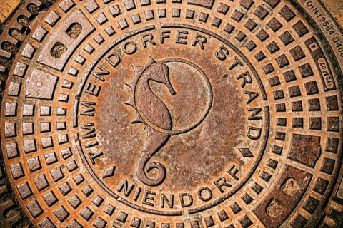 Manhole cover with seahorse symbol in Timmendorfer Strand, Schleswig-Holstein, Germany +++