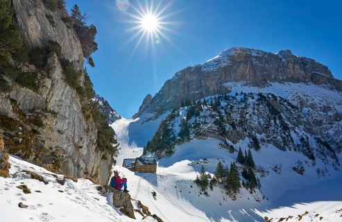 Woman hiking in the snowy mountain landscape of the Alpstein Säntis mountain range, Brülisau,