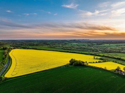 Sunset of Rapeseed Fields and Farms over Horsebridge nad Stockbridge from a drone, Hampshire,