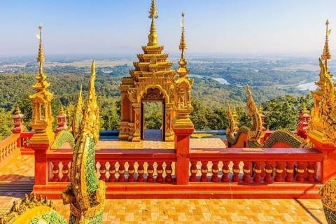 Gilded dragon figures, a gilded pagoda in the back, at the Buddhist temple Wat Phra That Don Phra