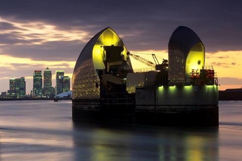 The Thames Barrier at dusk with Canary Wharf beyond, London, England, United Kingdom