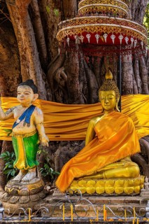 Gilded Buddha figure sitting under a canopy with orange cape, Wat Chiang Yuen Buddhist temple
