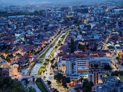 View of Prizren from above, Illuminated cityscape at night with a river, roads and bridges,