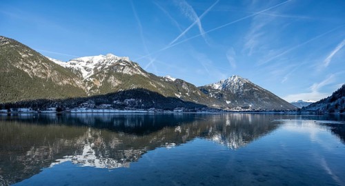 Winter snow-covered mountain peaks are reflected in the lake, Achensee, Tyrol, Austria