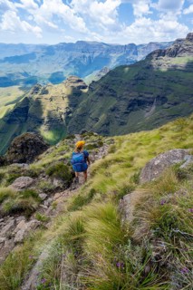 Female mountaineer hiking trail to Cathedral Peak or Cathedralpiek or Mponjwana, Drakensberg,