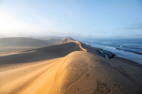Sand dunes in morning light, view of Atlantic coast and sea, Sandwich Harbour, impressive desert