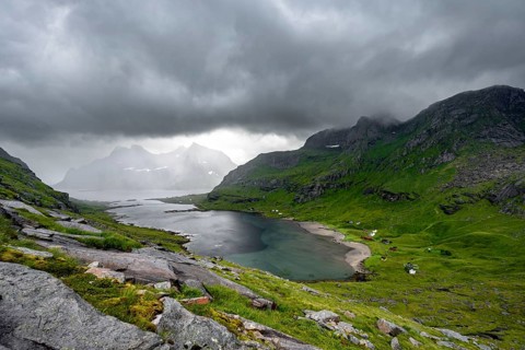 View over Bunesfjorden fjord, mountain peaks and dramatic clouds, climb to Helvetestinden summit,