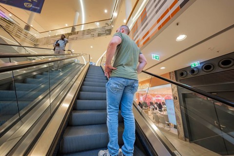 Man standing on escalator in a brightly lit shopping center, Milaneo, Stuttgart, Germany