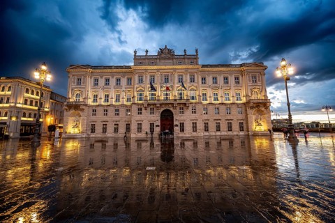 Illuminated square Piazza Unità d'Italia, Palazzo del Lloyd Triestino, with reflection, dramatic