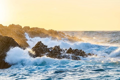 Braking waves at the coastline of Marinedda Coast at sunset, Sardinia, Italy