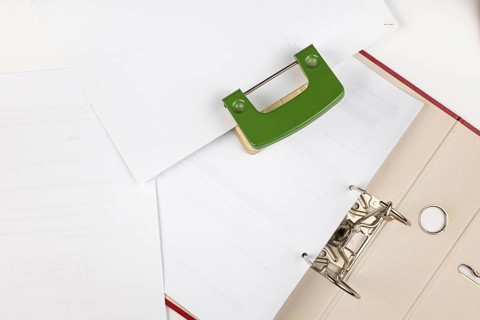 Paper and hole punches spread out on a desk with a folder